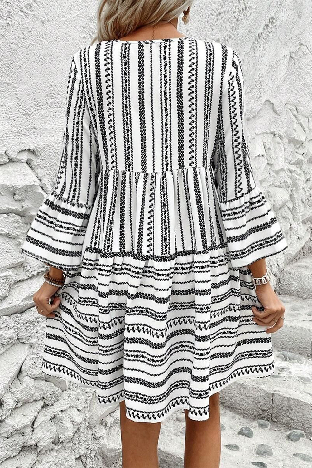 Vestido corto con escote en V, mangas acampanadas, cuello con lazo y flecos a rayas negras