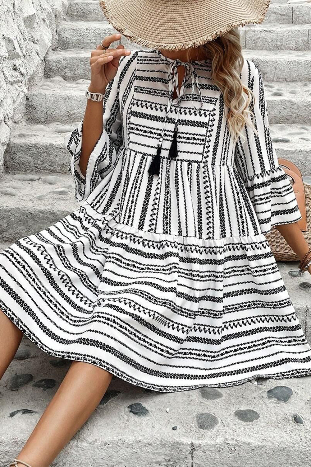 Vestido corto con escote en V, mangas acampanadas, cuello con lazo y flecos a rayas negras